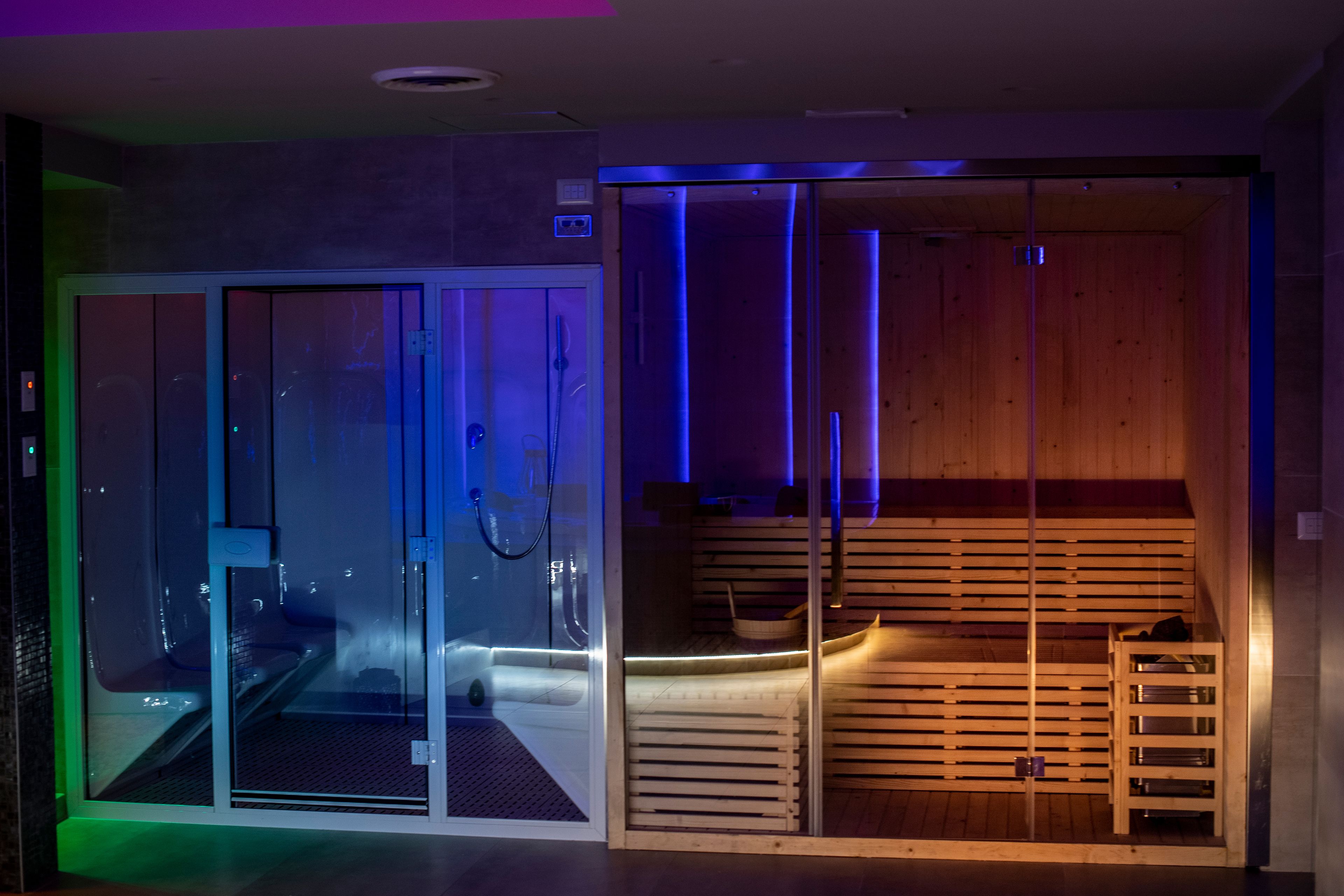 Een sauna met glazen deuren, houten banken en een bank met een handdoek.
