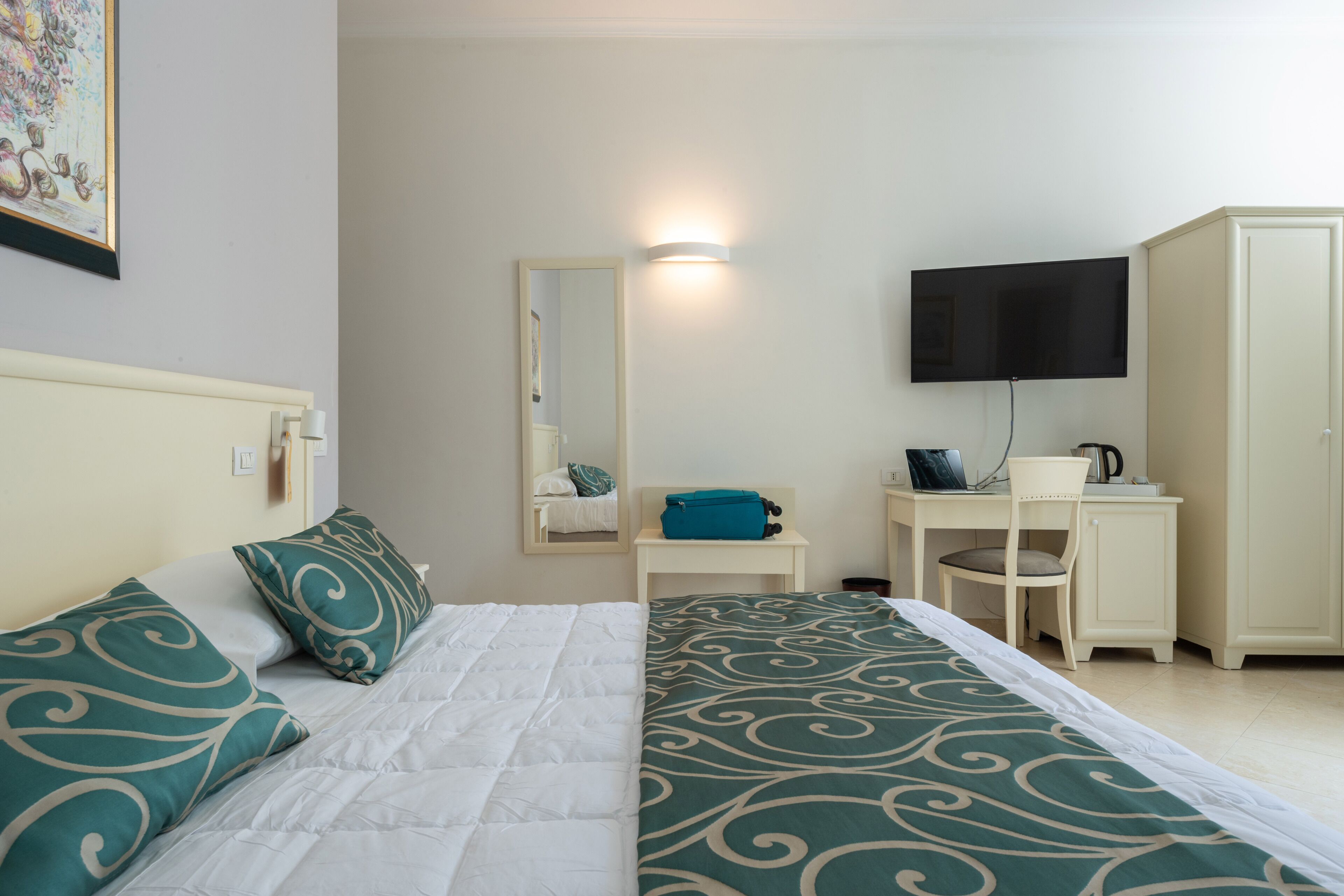 Une chambre d’hôtel équipée d’un lit, d’un bureau, d’une télévision et d’une armoire.