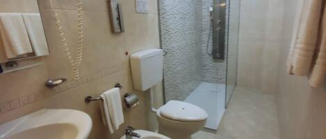 A bathroom with a sink, bidet, toilet, and a glass-enclosed shower.