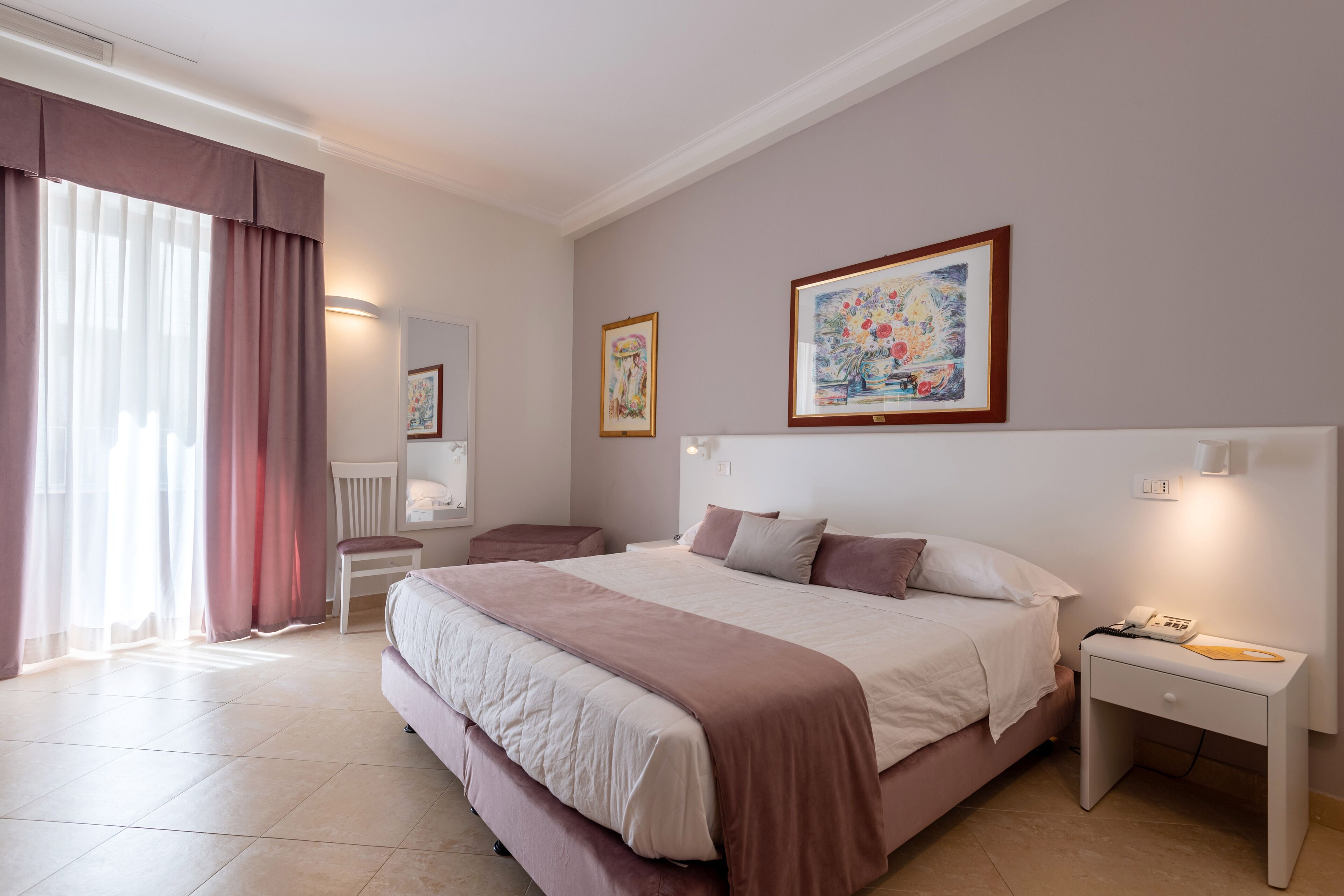 Una habitación de hotel moderna con una cama grande, una mesita de noche y un cuadro en la pared.