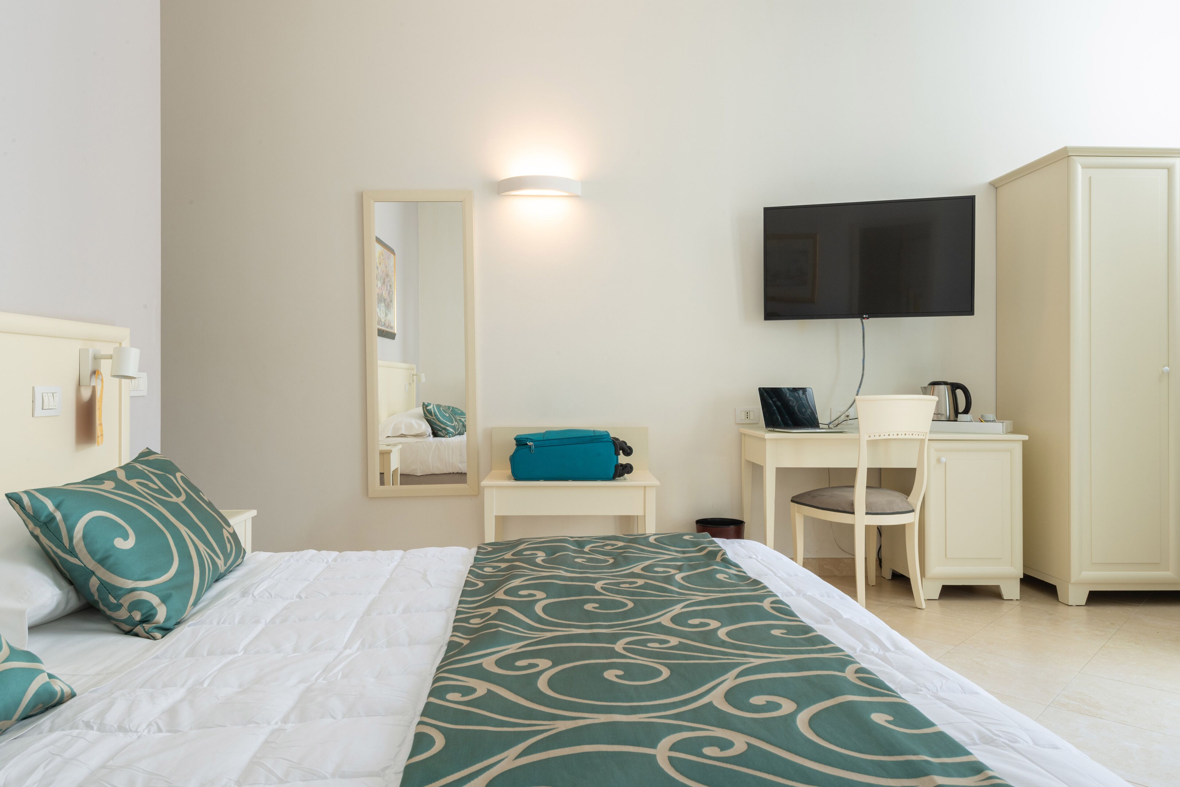 A hotel room with a bed, a desk, a television, and a wardrobe.