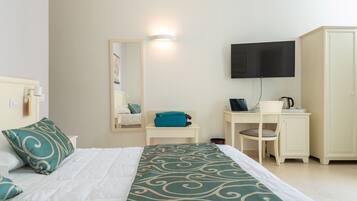 Quarto de hotel com cama, escrivaninha, televisão e guarda-roupa.