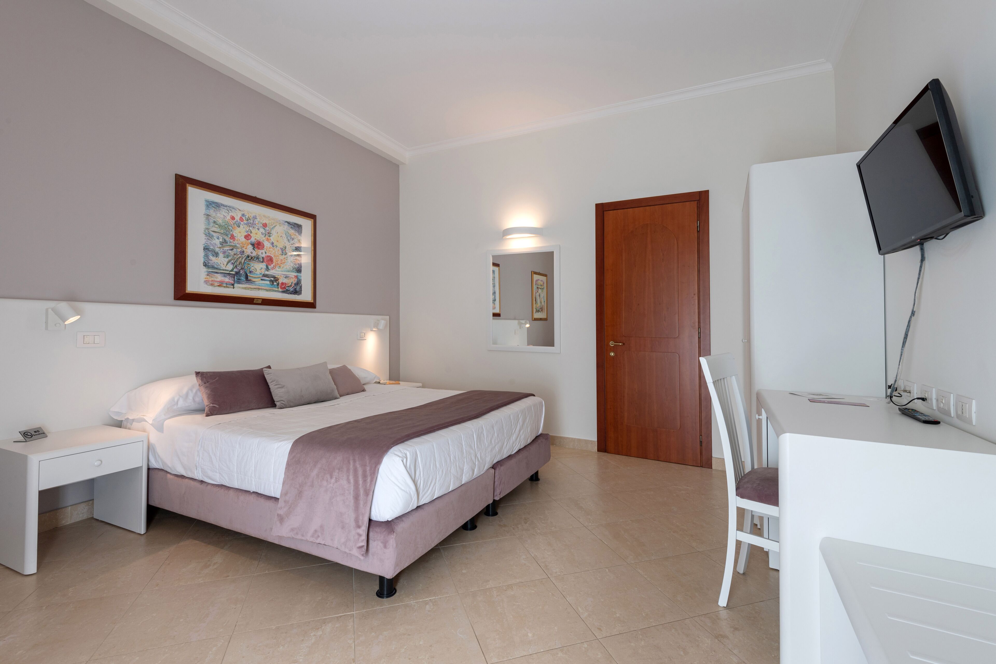 Une chambre à coucher comprenant un lit, une table de chevet, une télévision et un bureau avec une chaise.
