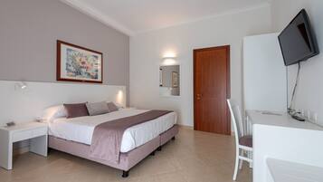 Une chambre à coucher comprenant un lit, une table de chevet, une télévision et un bureau avec une chaise.
