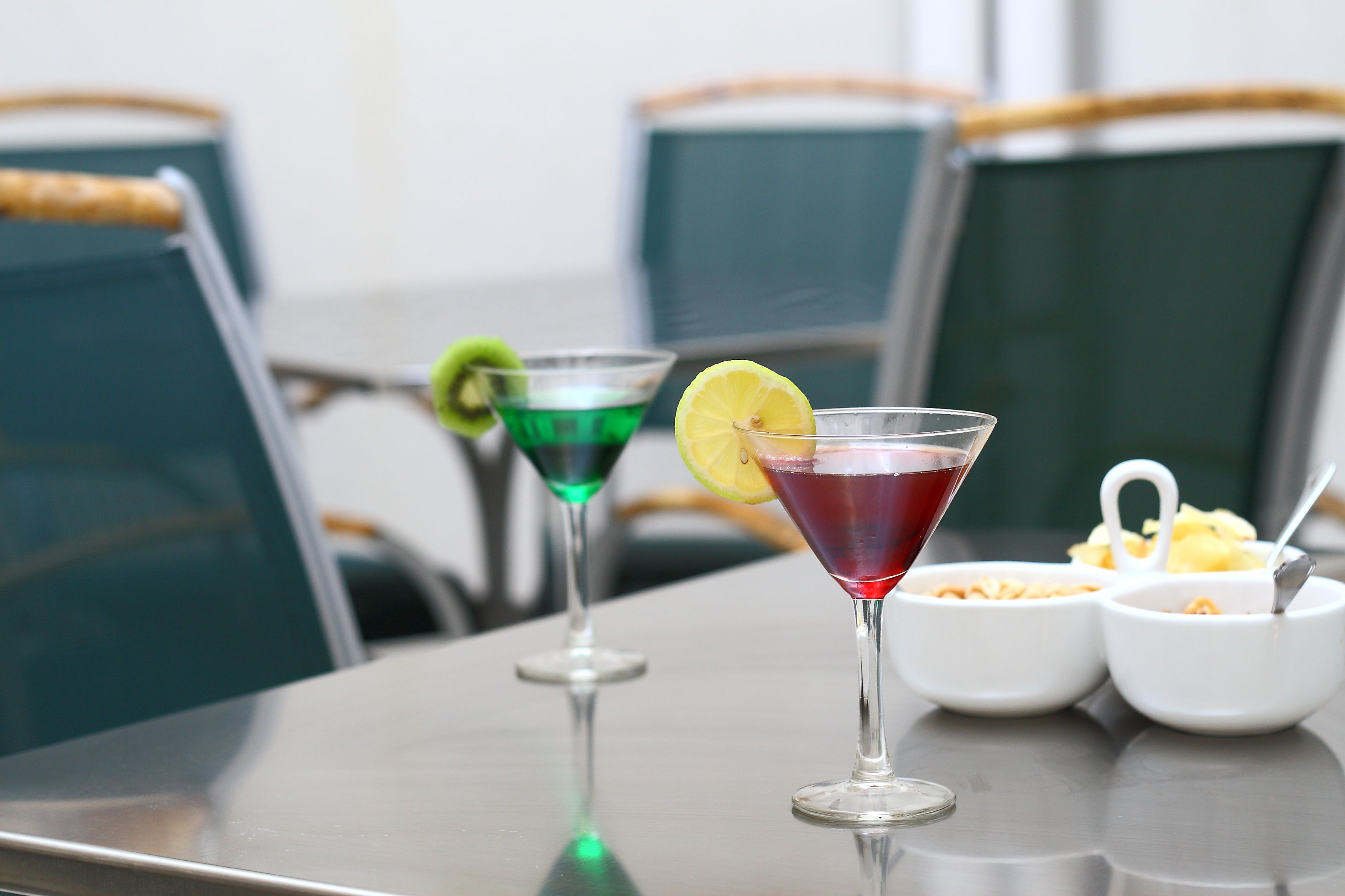 A table with two cocktails, a lemon slice, and two small bowls of cereal.
