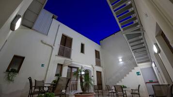 An indoor courtyard with a staircase, seating area, and potted plants.