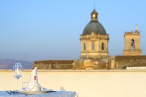 A dining table with a wine glass and napkin, set against a backdrop of a historic building with a dome and bell tower. - Hotel Centrale Spa & Relax (Alcamo)