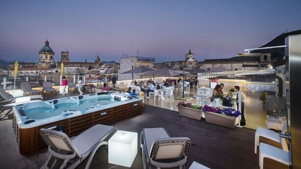 Een dakterras met een jacuzzi, lounge fauteuils en zitplaatsen buiten.