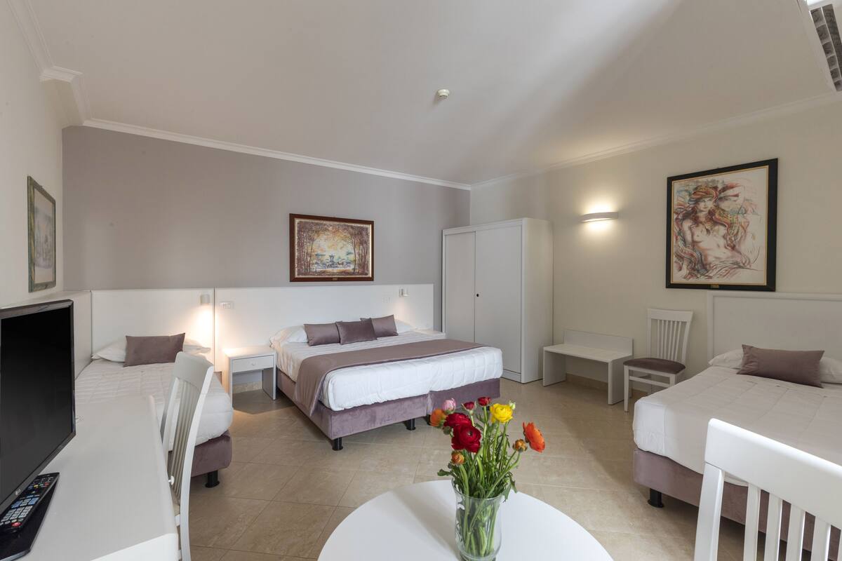 A hotel room with a bed, two bedside tables, a desk, a chair, and a TV.