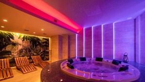 Een rond bubbelbad met zitplaatsen, een tropische muurschildering en een modern interieur.