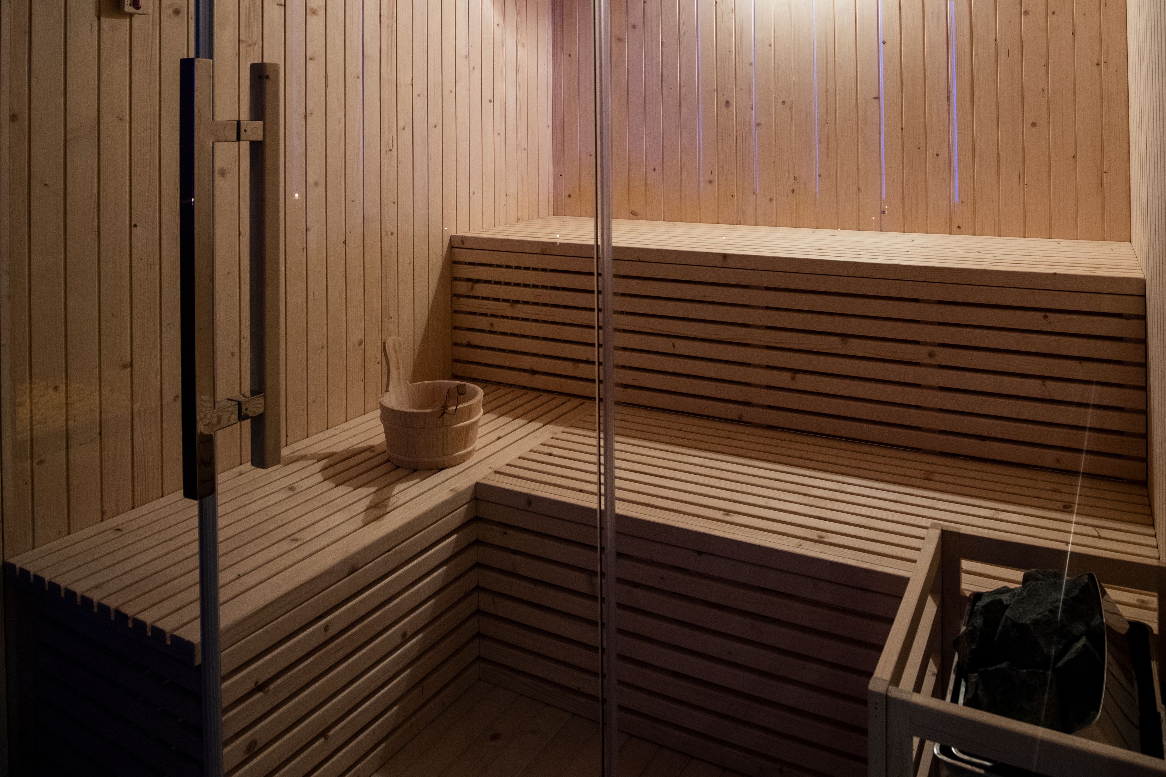 Una sauna con bancos de madera, un cuenco pequeño y un recipiente con piedras.