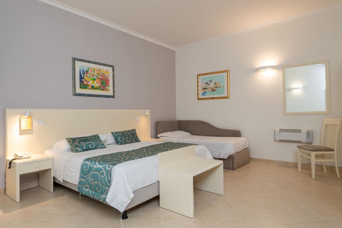 A hotel room with two beds, a desk, a chair, and a large mirror.