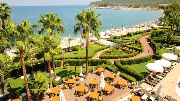 Un complexe hôtelier doté d’une terrasse extérieure offrant une vue sur la plage et la mer.