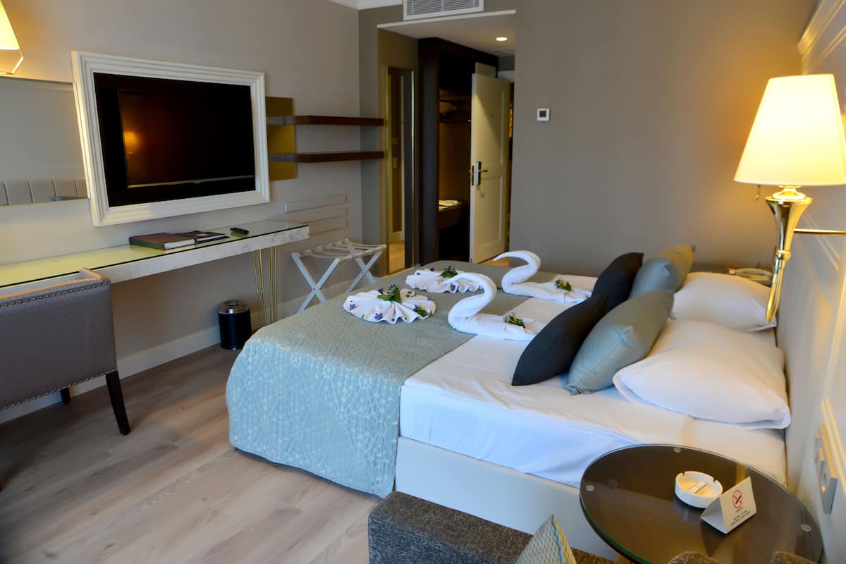 A hotel room with a bed, a desk, a TV, and a lamp.