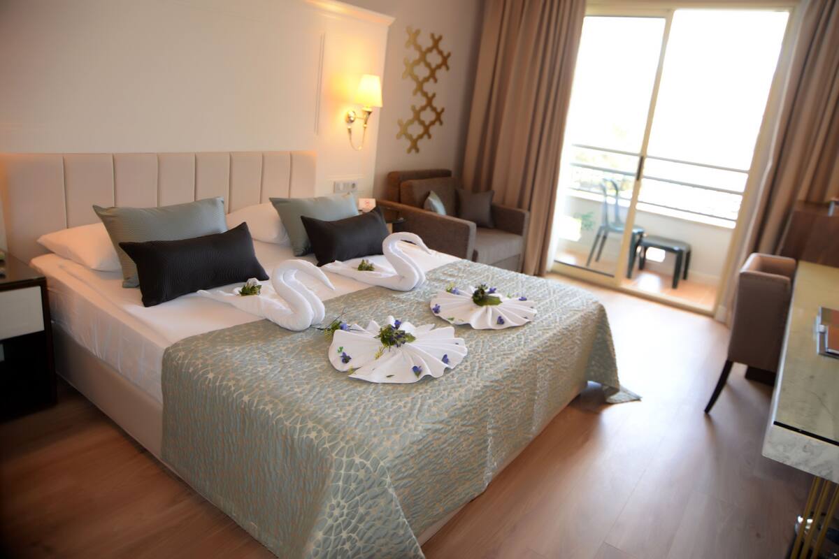 A hotel room with a bed, a sofa, a small table, and a window with curtains.
