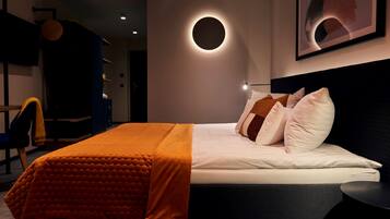 Ein modernes Hotelzimmer mit einem großen Bett, einer runden Wandleuchte und einem gerahmten Kunstwerk darüber.