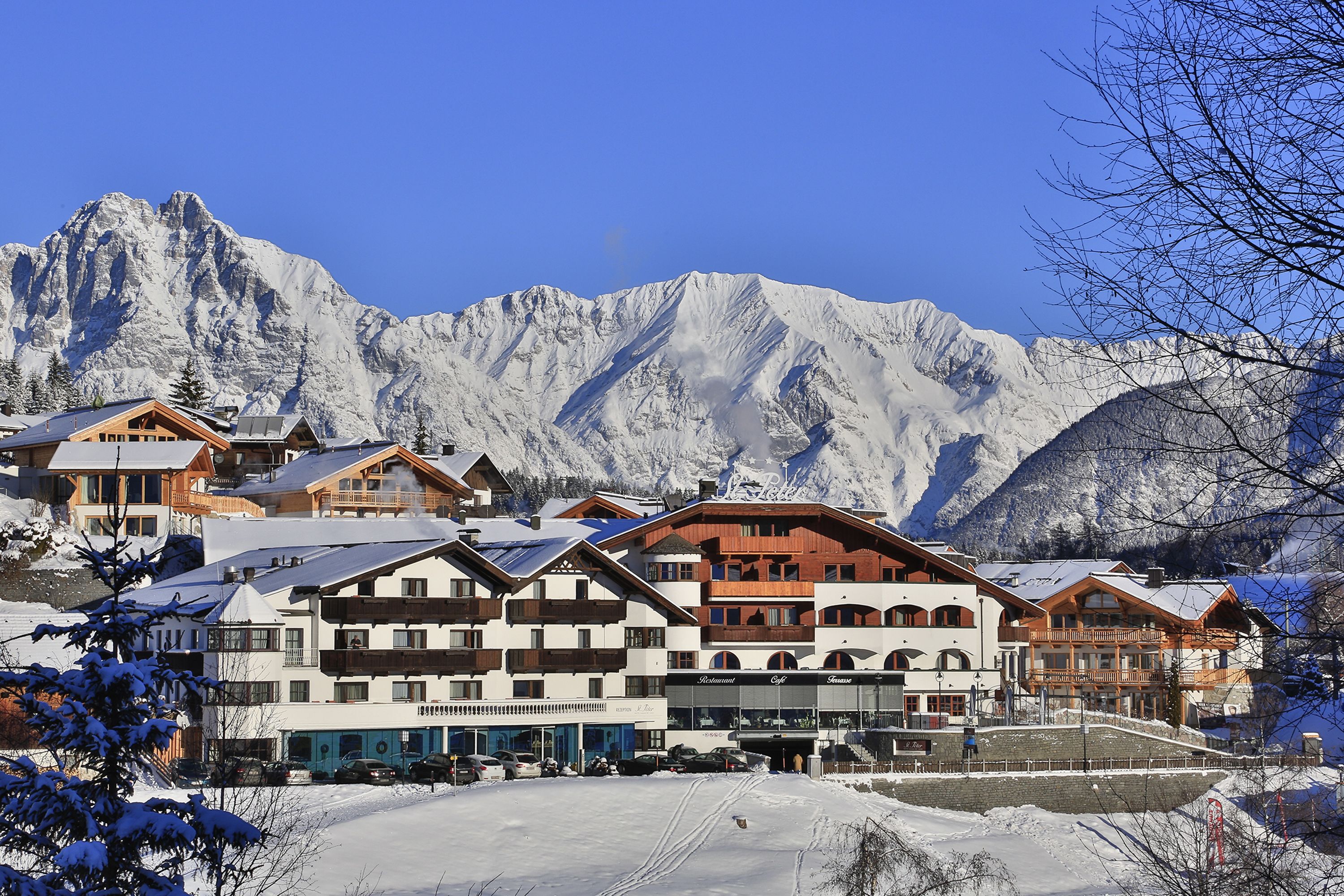 Ein Bergresort mit mehreren Gebäuden, darunter ein Restaurant und ein Spa, vor der Kulisse schneebedeckter Berge.