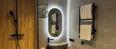 A modern bathroom with a glass-enclosed shower, a wooden vanity, a large mirror, and a towel rack.
