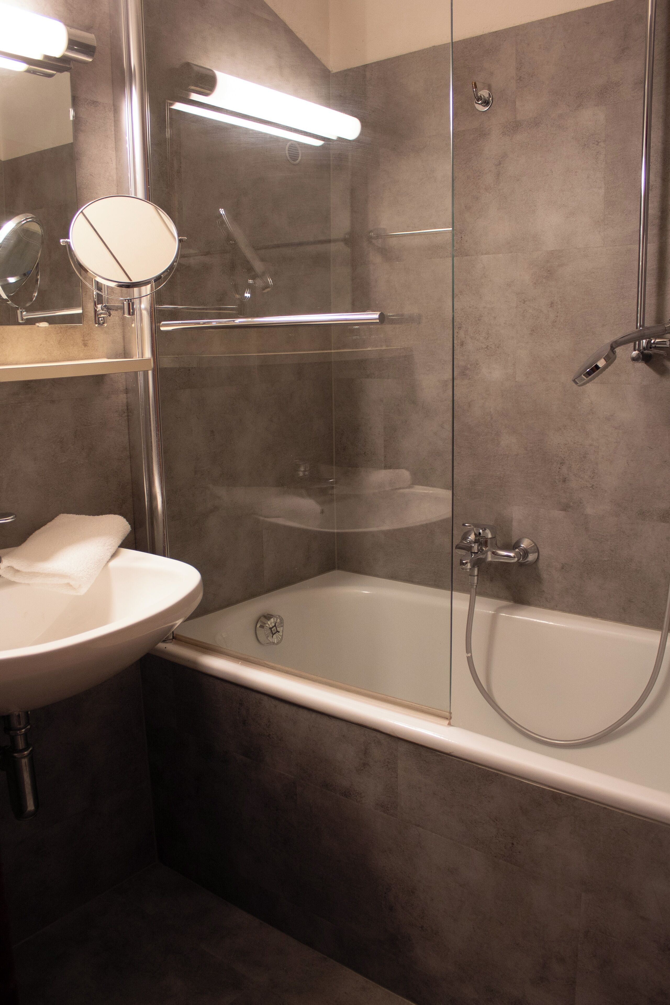 A modern bathroom with a glass-enclosed shower, a white sink, and a mirror.