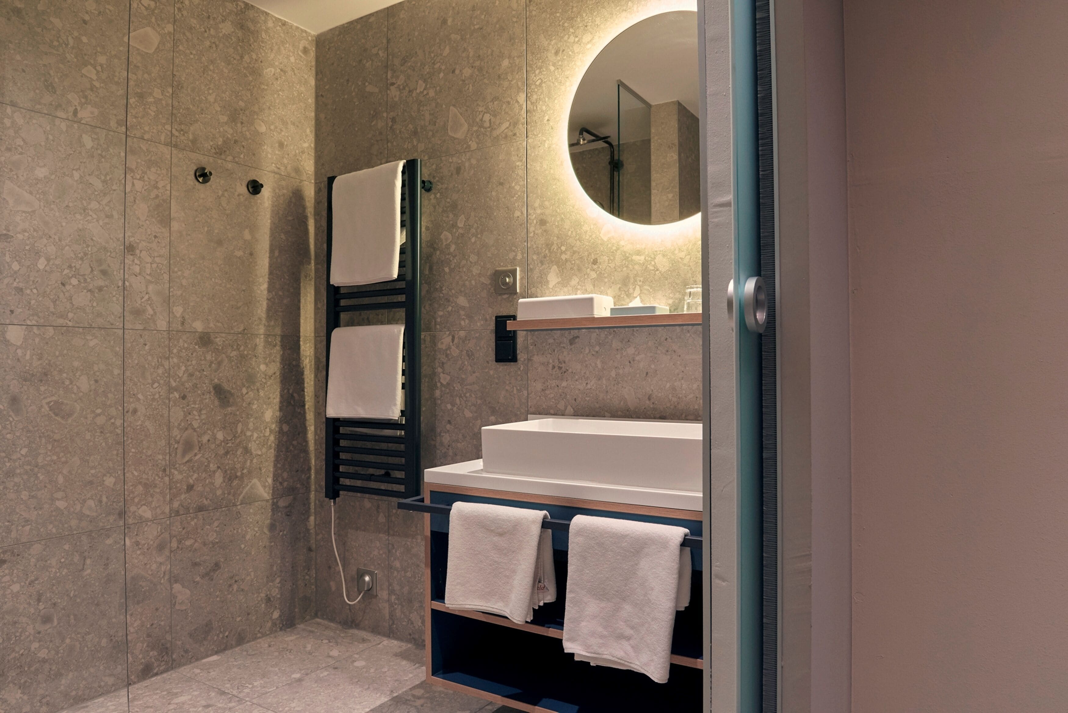 A modern bathroom with a freestanding bathtub, a towel rack, and a mirror.