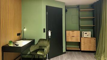 A compact room with a desk, chair, and a small cabinet with a microwave.