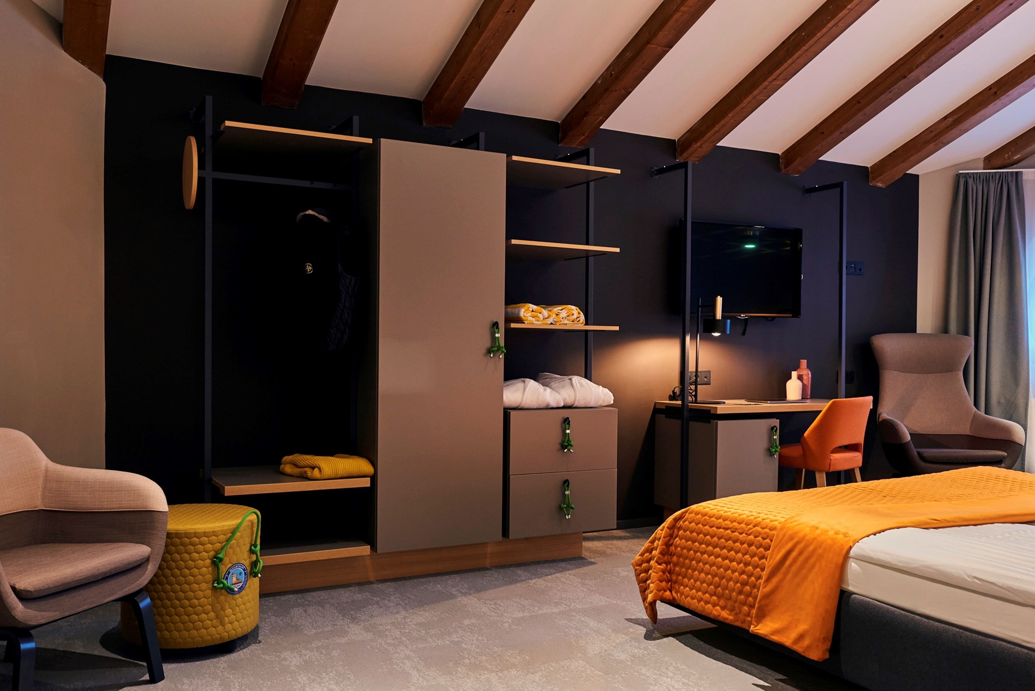 Ein modernes Hotelzimmer mit Bett, Schreibtisch, Fernseher und Kleiderschrank.