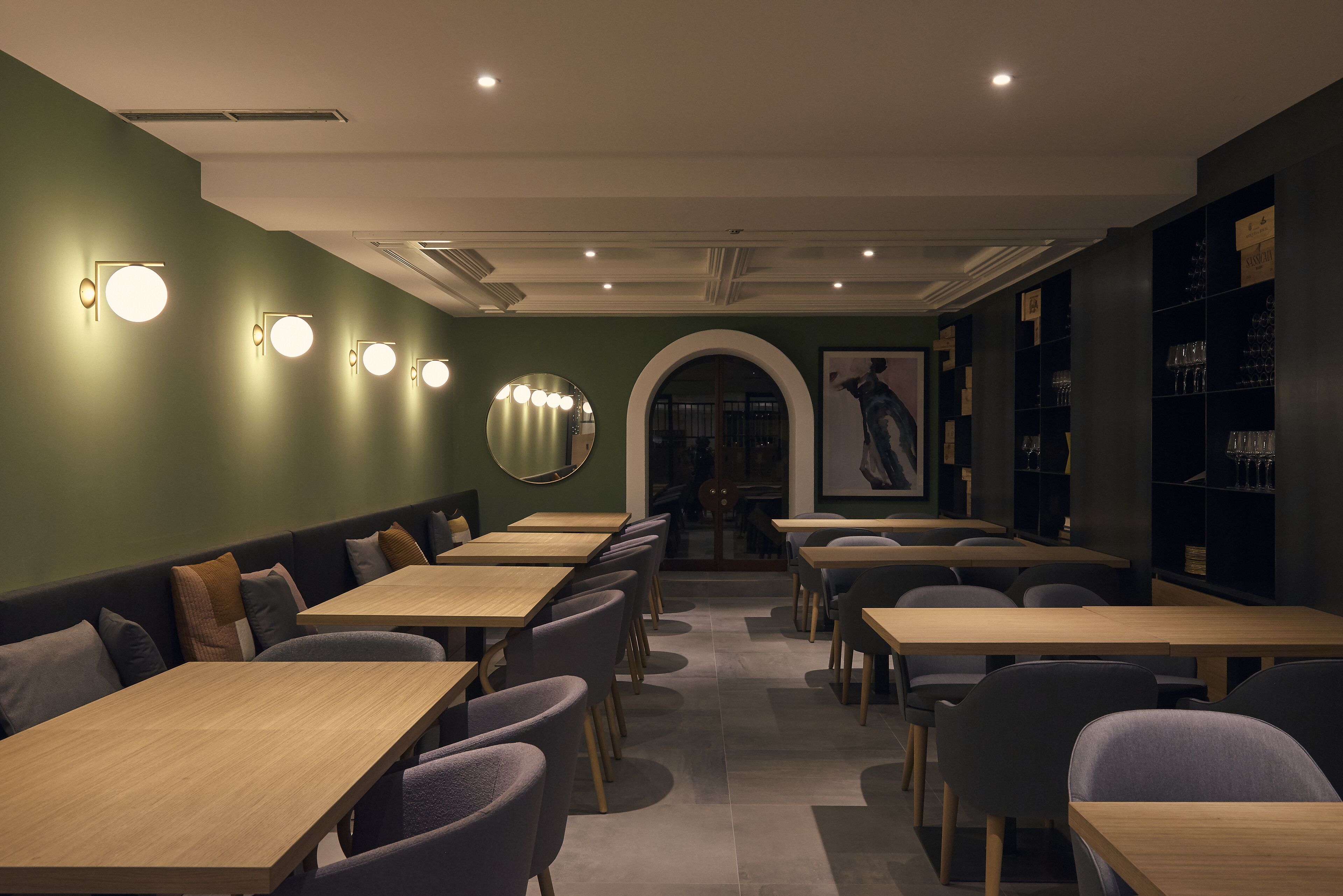 A restaurant interior with booths and tables, a mirror, and wall-mounted lights.