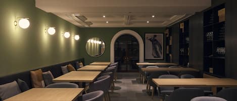 A restaurant interior with booths and tables, a mirror, and wall-mounted lights.
