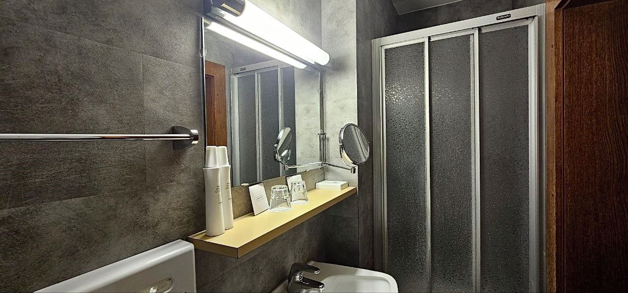 A bathroom with a vanity, a mirror, a towel rack, a shower enclosure, and a toilet.