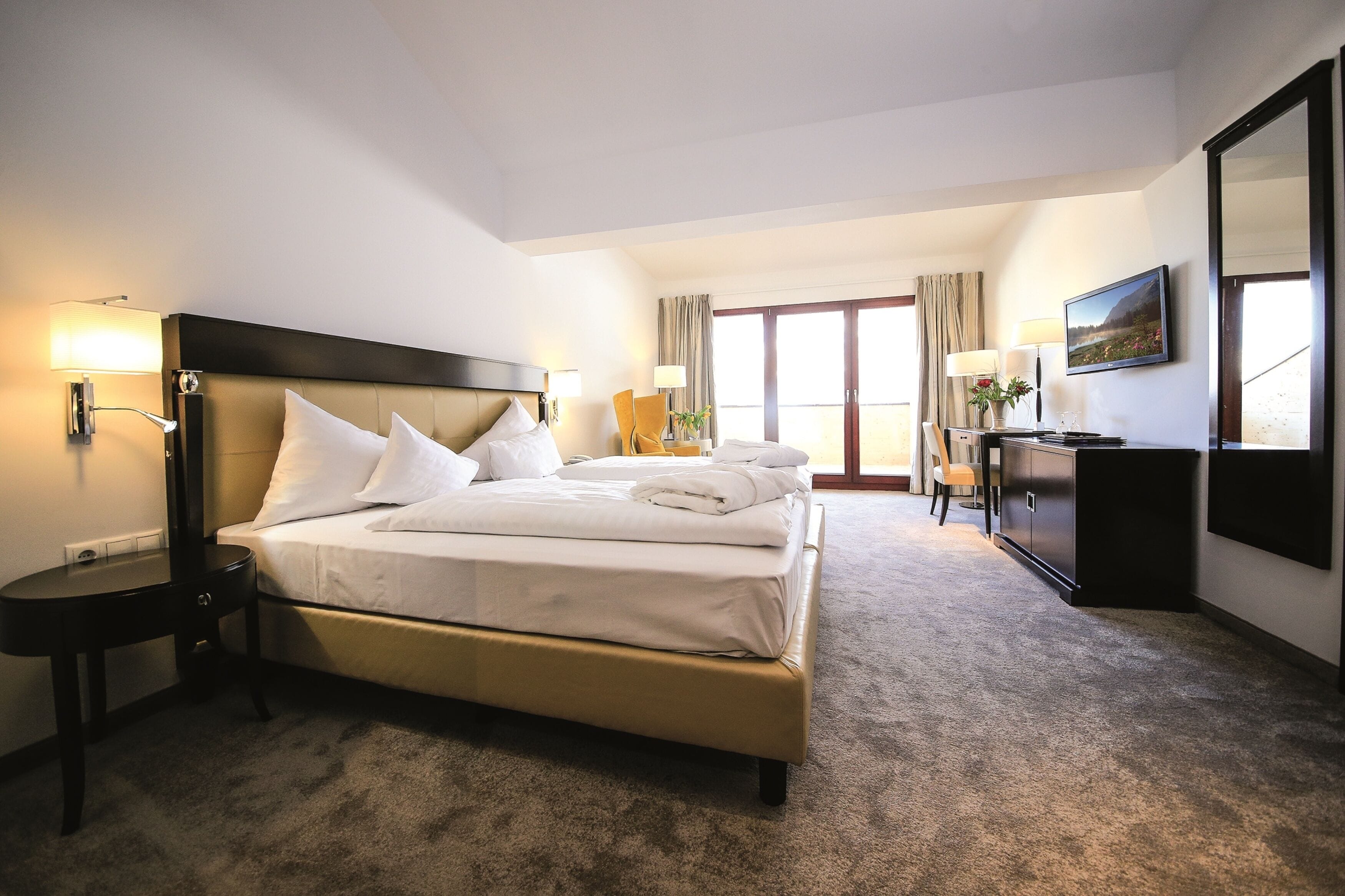 Une chambre d’hôtel avec un grand lit, des tables de chevet, un bureau et une chaise.