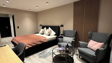 Une chambre d’hôtel moderne, équipée d’un lit, de deux fauteuils, d’une petite table et d’un tapis en fourrure.