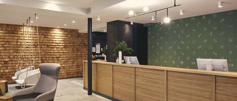 A modern reception area with a wooden reception desk, a grey office chair, and a hanging light fixture.