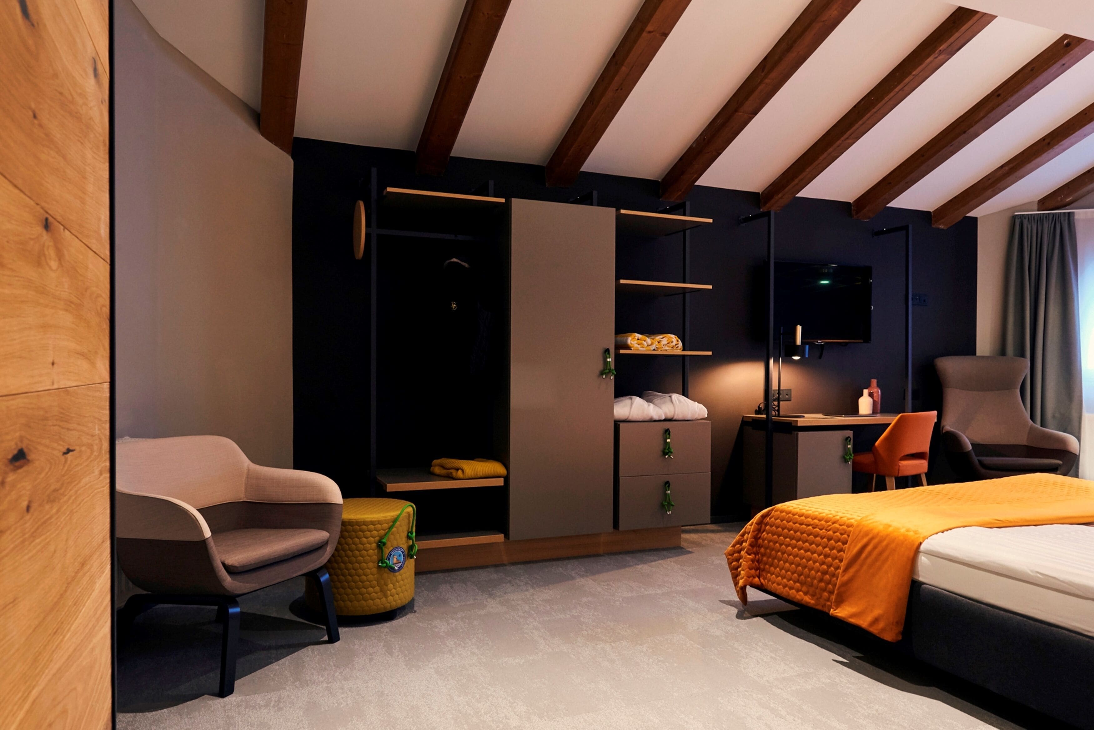 Una camera d'albergo moderna con un letto, una scrivania, una sedia e un armadio.
