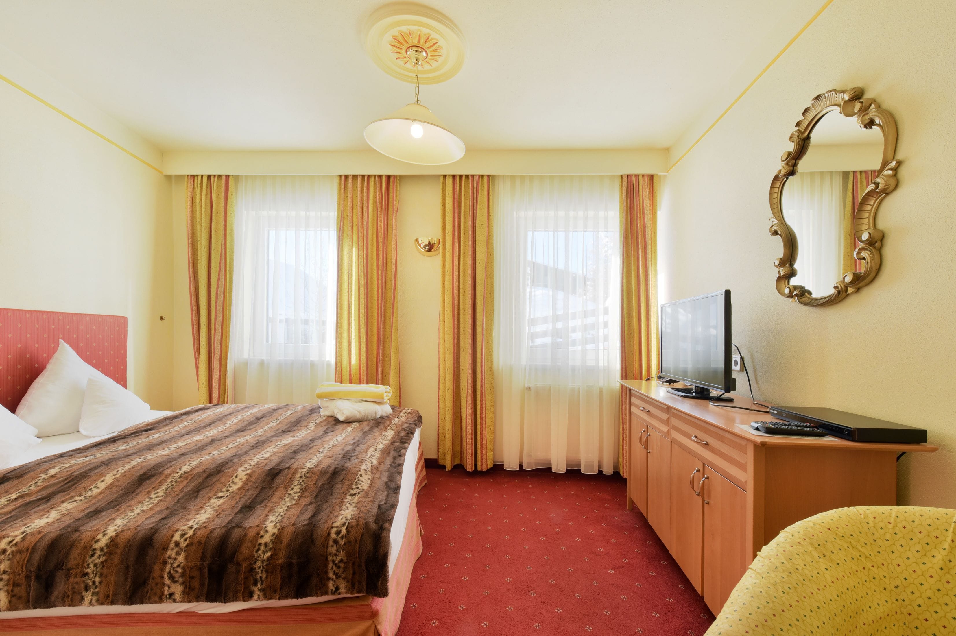 A hotel room with a bed, a television, a desk, and a mirror.