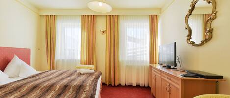 A hotel room with a bed, a television, a desk, and a mirror.