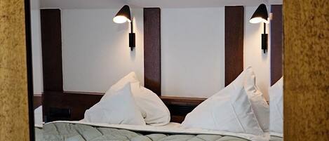 A hotel room with a bed, two wall-mounted lamps, and a wooden headboard.