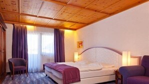 Ett hotellrum med en säng, en stol, en soffa och ett fönster med gardiner.