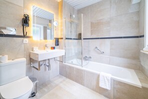 A modern bathroom with a glass-enclosed shower, a white sink, and a toilet. - Grand Hotel Normandy by CW Hotel Collection (Bruges)