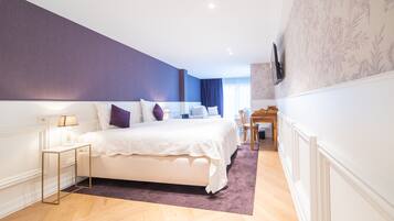 Een moderne slaapkamer met een groot bed, een nachtkastje, een bureau en een stoel.