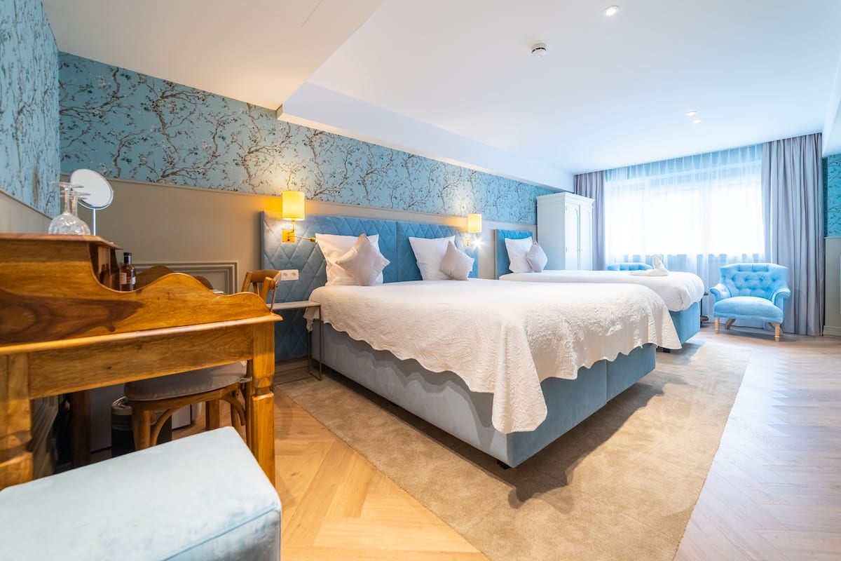 A modern hotel room with a large bed, a desk, and a chair.
