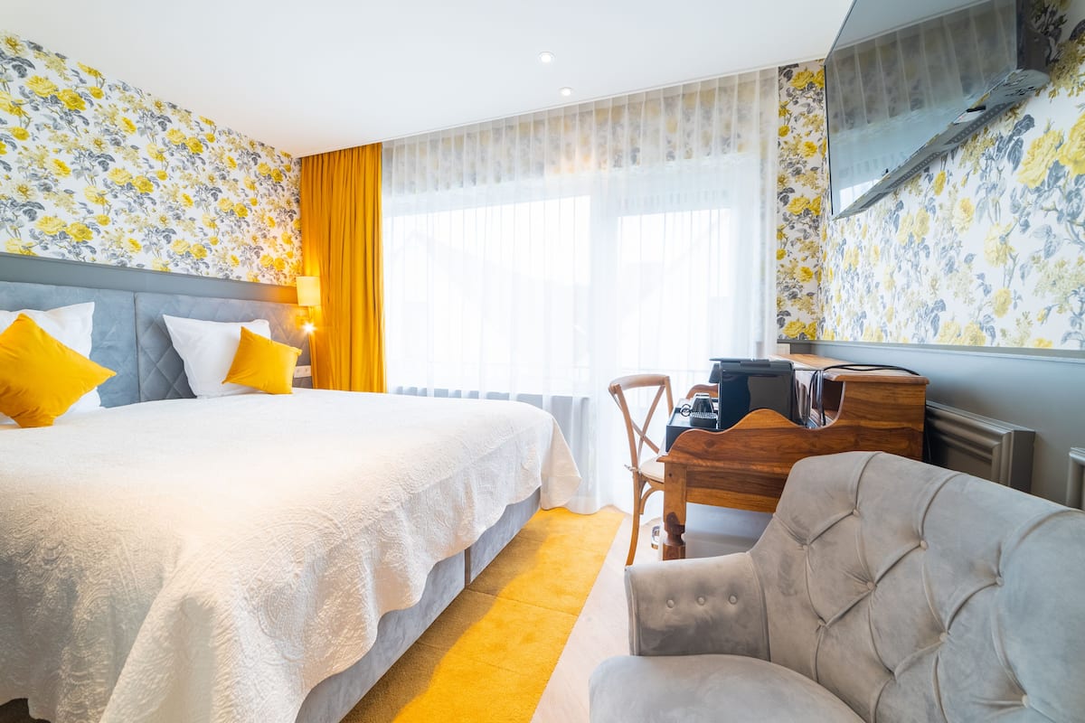 A hotel room with a large bed, a desk, and a chair.