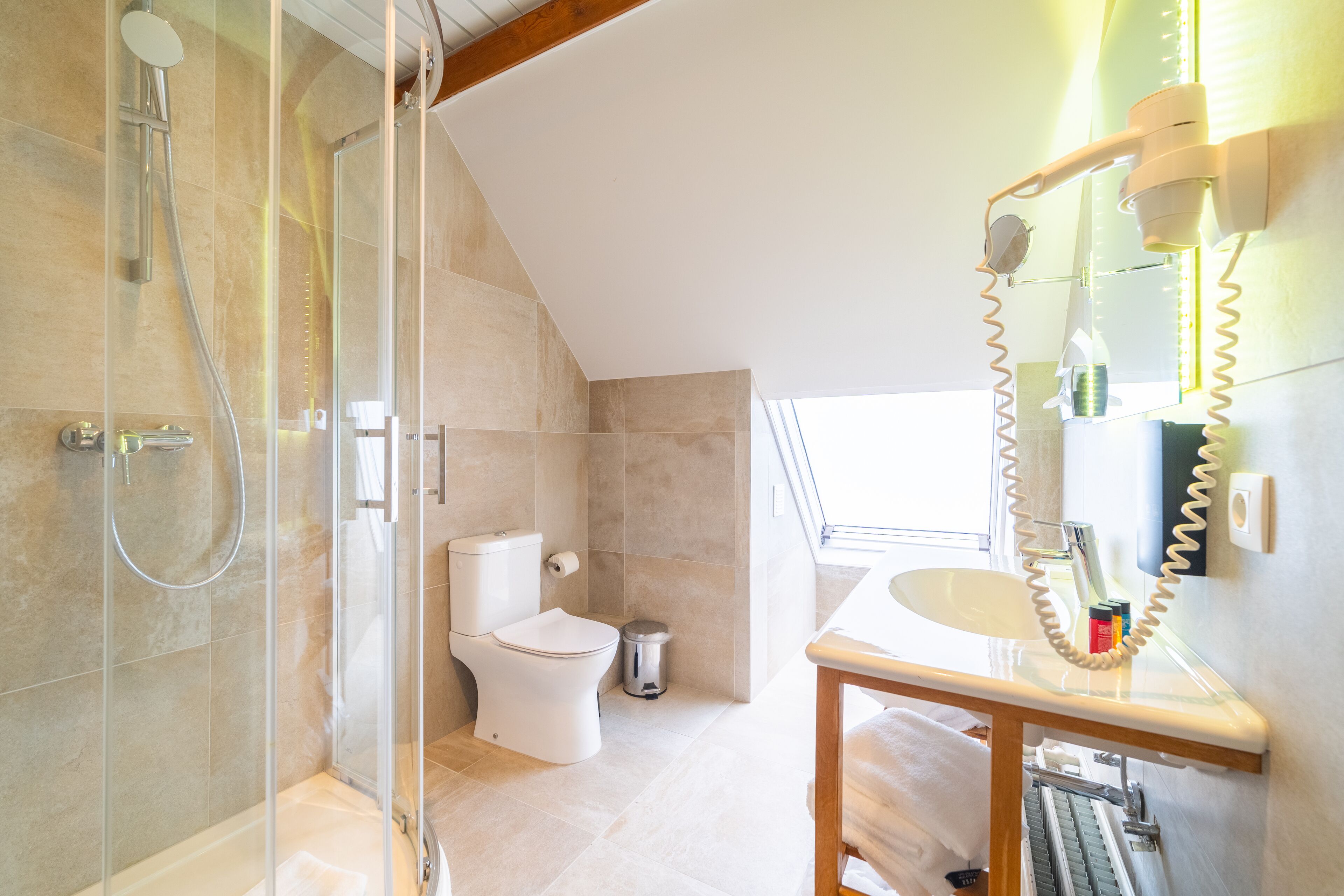 A modern bathroom with a glass-enclosed shower, a toilet, and a vanity with a mirror and towel rack.
