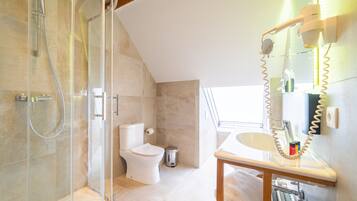 A modern bathroom with a glass-enclosed shower, a toilet, and a vanity with a mirror and towel rack.