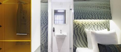 A hotel room with a bed, a bathroom with a sink, and a wardrobe.
