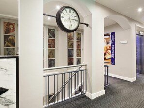 A hallway with a clock, a staircase, and a sign for the breakfast room. - ibis Styles Amsterdam Central Station (Amsterdam)