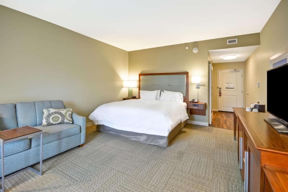 A hotel room with a bed, a sofa, a TV, and a desk.