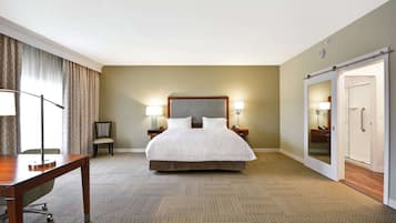 A hotel room with a large bed, bedside lamps, a desk, and a wardrobe.