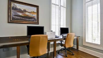 A workspace with two desks, two chairs, two monitors, and a printer.