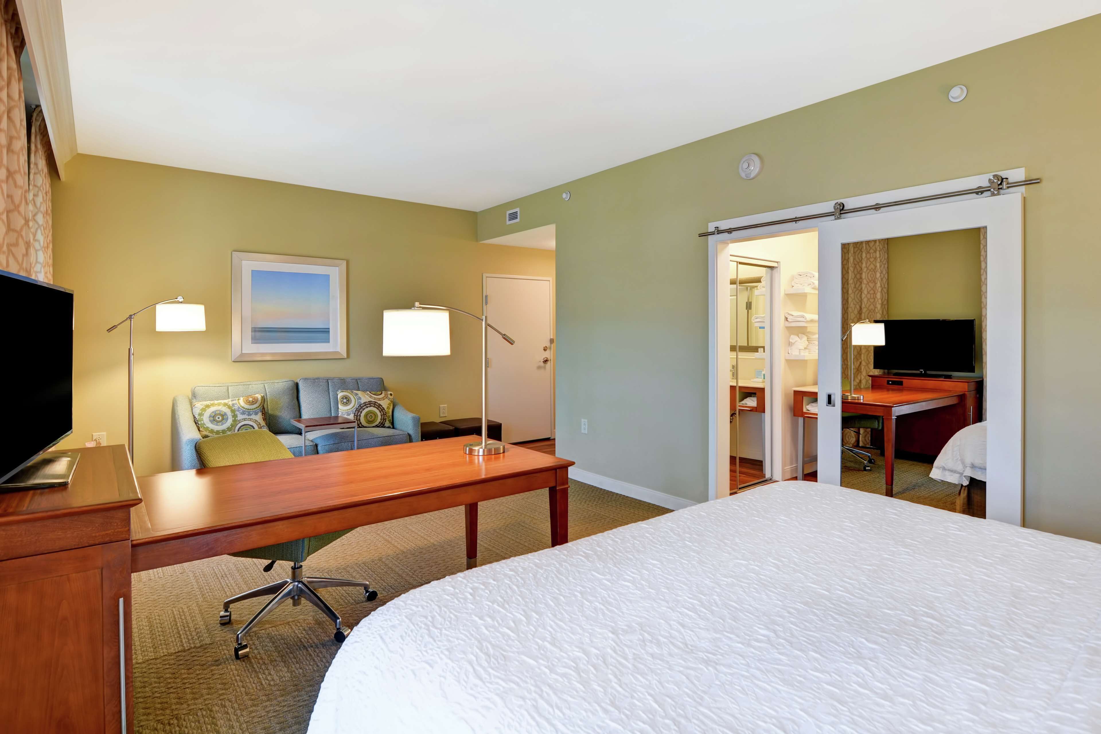 A hotel room with a bed, a desk, a sofa, and a TV.