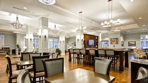 A spacious hotel lobby with high ceilings, modern chandeliers, and a variety of seating arrangements including tables and chairs. - Hampton Inn & Suites Charleston Airport (North Charleston)